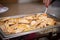 Closeup shot of cooked meat piled in a chafing dish being served from a buffet table