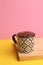 Closeup shot of a cup full of chocolate pudding on a pink background