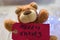 Closeup shot of a cute brown toy bear holding the label \\\