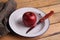 Closeup shot of a delicious and bright red apple and a knife on a white plate