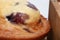 Closeup shot of a delicious cherry jam cupcake next to a wooden box on a white surface