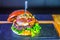 Closeup shot of a delicious open burger with fresh ingredients attached with skewers stick