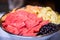 Closeup shot of different chopped fruits in a metal pan with a blurred background