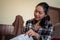 Closeup shot of an East Asian woman opening a package, looking to the cloth in it on the sofa