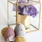 Closeup shot of egg-shaped glitter decorations, a rabbit egg and purple artificial flowers