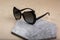 Closeup shot of elegant black sunglasses on a grey stone surface on a beige background