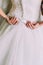 Closeup shot of elegant, bride in vintage white dress fixing her dressing at wedding preparations. Back view