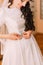 Closeup shot of elegant, brunette bride in vintage white dress fixing her dressing before wedding