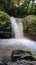 Closeup shot of a fast-flowing stream on the mountain rocks, a small waterfall - vertical shot