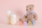 Closeup shot of feeding bottles, toy bear and baby word from colorful wooden letters