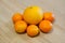Closeup shot of five tangerines around an orange on a wooden surface