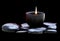 Closeup shot of a flame in a cup with smooth rocks isolated on a dark background