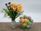 Closeup shot of flowers in a vase with Easter eggs in a bowl on a table