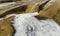 Closeup shot of the foam of the river flow on the brown rocks of the riverbank