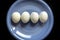 Closeup shot of four boiled peeled eggs on a blue plate