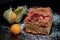 Closeup shot of a freshly baked cake with raspberries, jostaberries and rhubarb on a black plate isolated on black background with