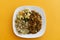 Closeup shot of fried rice, Chinese noodles with chicken, veggies isolated on a yellow background