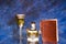 Closeup shot of a goblet, a drink resembling potion, and a notebook on a glass table