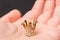 Closeup shot of a gold small crown on a person\'s palm