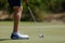 Closeup shot of a golf player's legs near the golfing ball hole