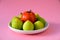 Closeup shot of green figs bowl with a single tomato isolated on pink background