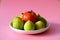 Closeup shot of green figs bowl with a single tomato isolated on pink background