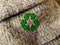 Closeup shot of a green recycling arrow icon on an old woolen sweater