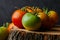 Closeup shot of green and red tomatoes on a tree stump on a black background