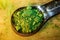 Closeup shot of green tea powder on a metallic, measuring spoon