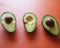 Closeup shot of a group of avocados on an orange background