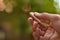 Closeup shot of a hand holding caliber bullet against green bokeh background