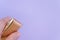 Closeup shot of a hand holding gold miniature bag isolated on purple  background