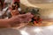 Closeup shot of a hand placing decorative beautiful flowers near a cream wedding cake