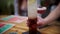 Closeup shot of a hand setting a tall long island iced tea drink on a table