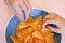 Closeup shot of hands of a couple reaching for triangular chips in a blue bowl