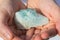 Closeup shot of hands holding a beautiful natural green precious mineral geode stone