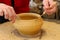Closeup shot of the hands of a potter creating a jar