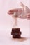 Closeup shot of hands powdering cacao powder on a piece of freshly baked chocolate brownie cake