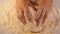 Closeup shot of hands of senior bakery chef applying flour on dough