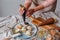 Closeup shot of hands of a woman preparing and decorating cinnamon rolls