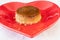 Closeup shot of a homemade flan pudding on a red heart-shaped plate