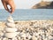 Closeup shot of a human hand putting the beautiful white stones of the seashore on each other