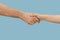 Closeup shot of human holding hands isolated on blue studio background.