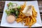 Closeup shot of Icelandic fish with chips, vegetable
 and fries on a white plate