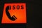 Closeup shot of an illuminated SOS sign with a telephone icon