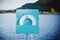 Closeup shot of a lifebuoy placed on a blue column and the sea in the background - SOS concept