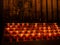 Closeup shot of lit votive prayer candles in a church in front of a Saint Mary statue