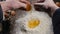 Closeup shot of male chef cracking egg in glass bowl with flour. Slow motion of falling eggs into flour stock. Footage