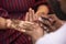 Closeup shot of a male drawing on a female\'s hand with brown henna