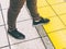 Closeup shot of male feet stepping on yellow sidewalk tiles